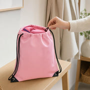 Open pink drawstring bag with black cords, reinforced black corners and several smaller pink and purple kit pieces inside.