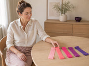 Woman choosing from five flat loop bands arranged from pale pink to deep purple.